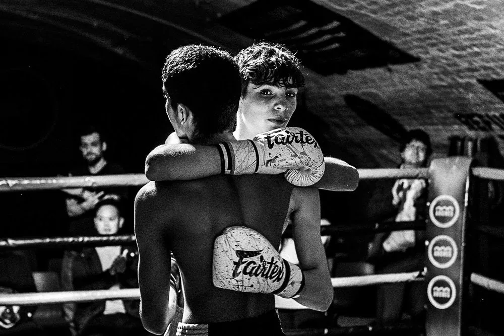 Two Muay Thai fighters embrace in the ring after a bout in Chiang Mai